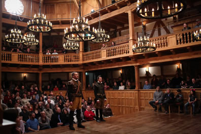 Photo of Rosencrantz and Guildenster standing on the edg of the stage, their backs to the audience with the full of the Blackfriars Playhouse interior in the background