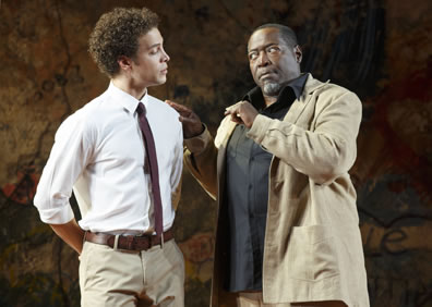 Paris in white shirt, khaki pants, brown belt and thin brown tie, and Capulet in brown leisure suit with black shirt, his hand on Paris' shoulder.