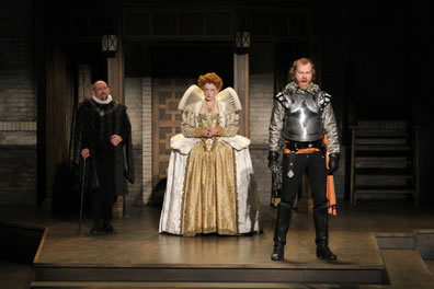 Cecil in black cloak with ruff collar, Elizabeth in gold dress with white trim, gold embroidered corset and jacket with high, spread-out collar, Essex in armor and black pants