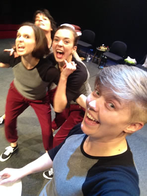 A selfie with a smiling Davidson in front and crowded behind the three actresses playing Weird Sisters wearing red sweat pants and two-tone blue t-shirts