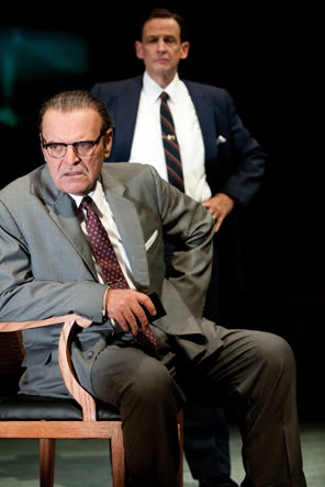 LBJ in gray suit sitting in chair with HHH standing behind him in blue suit with hands on hips
