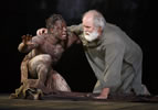 Edgar in only a loin cloth around his waist and hand up, kneels with Lear, in simple burlap-like rope, one hand on the groound,the other around Edgar's shoulder