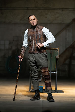 Production pic of Richard III with leather vest, knee brace, and cane.