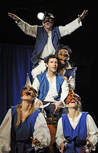 The 2012 cast in blue vests, all in masks except Romeo, form the Queen Mab visual: Benvolio on top with arms outstretched, Mercutio speaking over Romeo's shoulder, two servants at the bottom.
