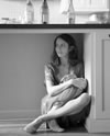 Beatrice sitting in the nook underneath a kitchen counter, with wine bottles on the countertop